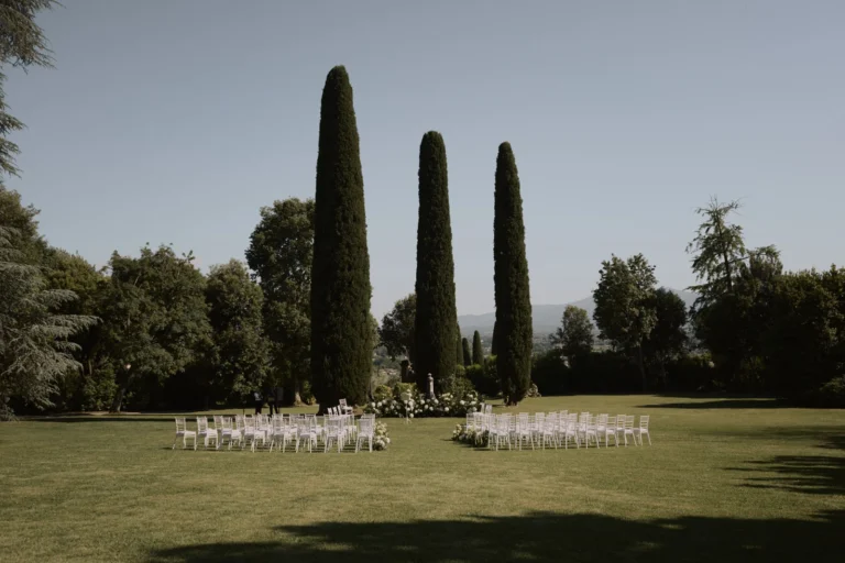 Cerimonia di matrimonio in Toscana all'aperto, sedie bianche tra cipressi e ortensie nel giardino della villa