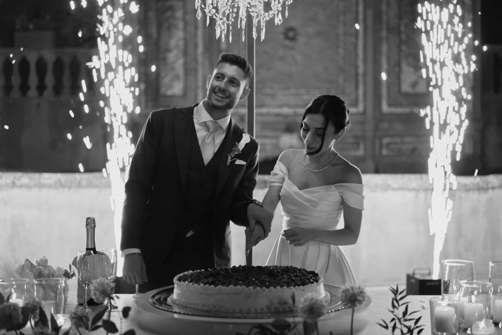 Taglio della torta nuziale con fontane luminose durante il ricevimento di matrimonio in Toscana