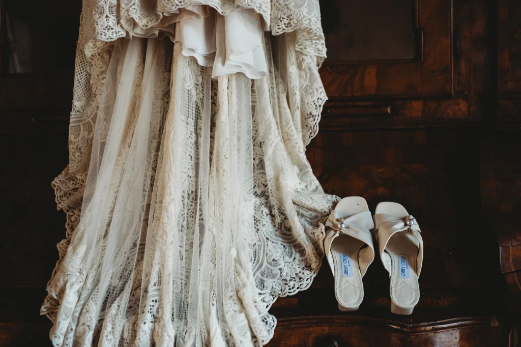 Dettaglio dell'abito da sposa in pizzo e delle scarpe bianche negli interni storici di Villa Gaia Gandini